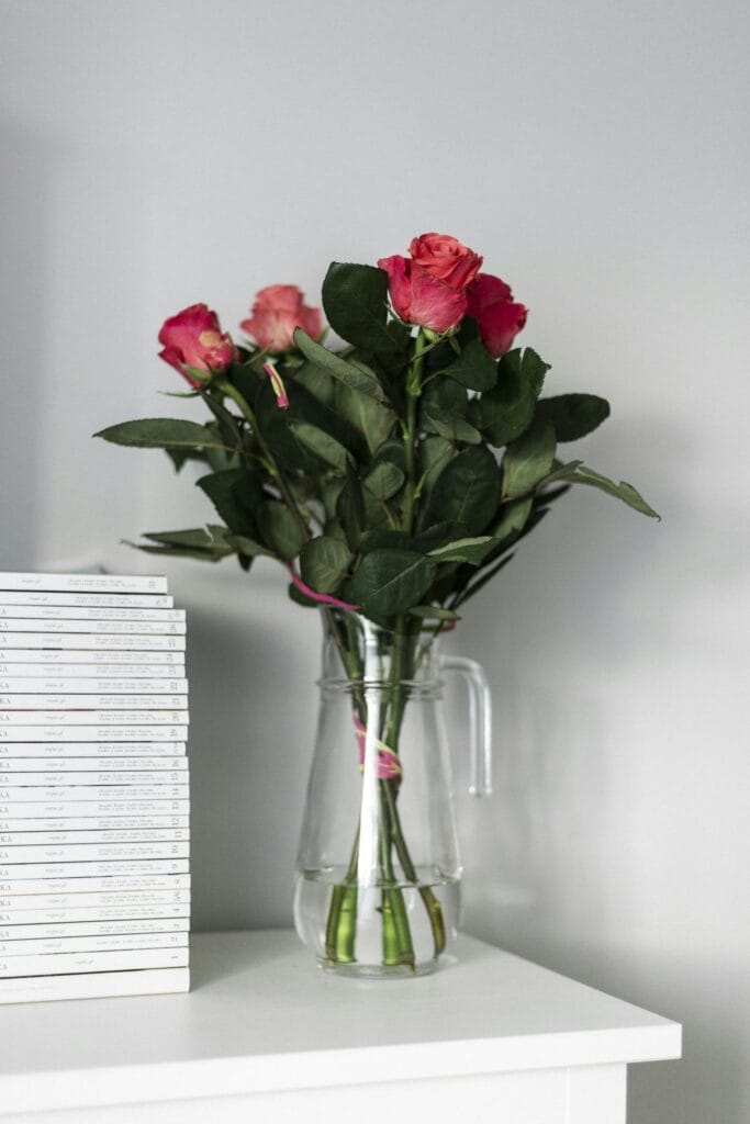 Beautiful pink roses arranged in a glass vase on a white table, perfect for home decor.