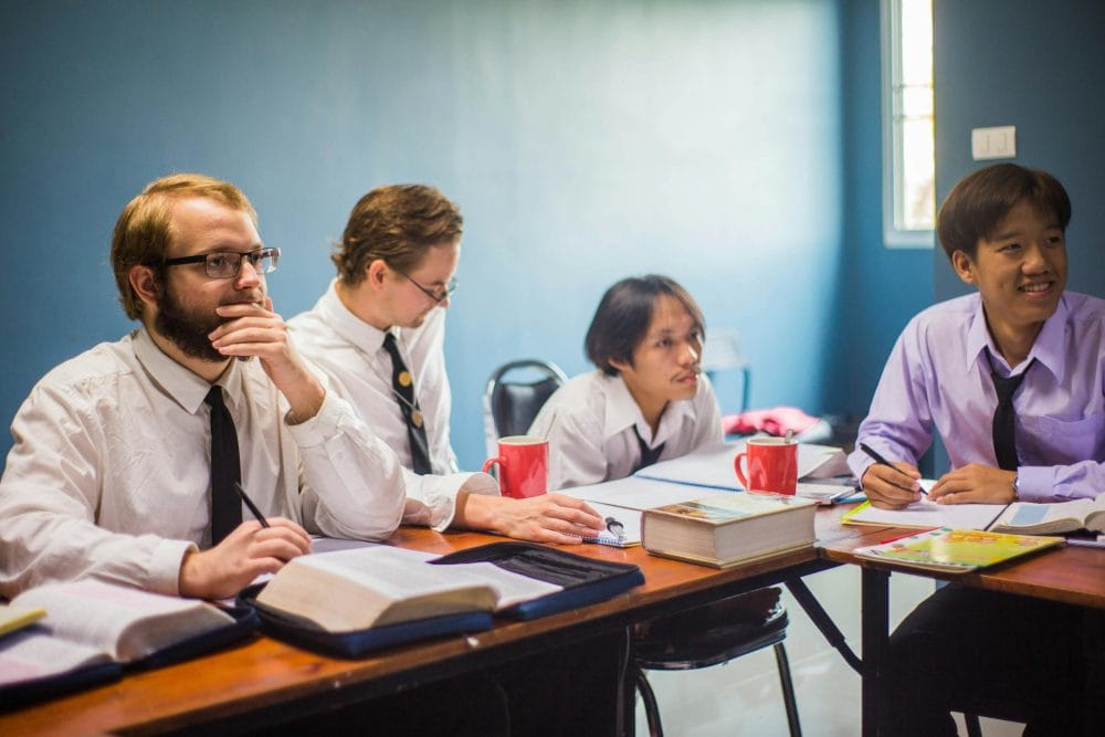 Group of students with books focusing on a study session in a classroom.